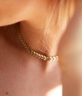 cuello de mujer rubia con collar gargantilla dorado con diseño de espiga