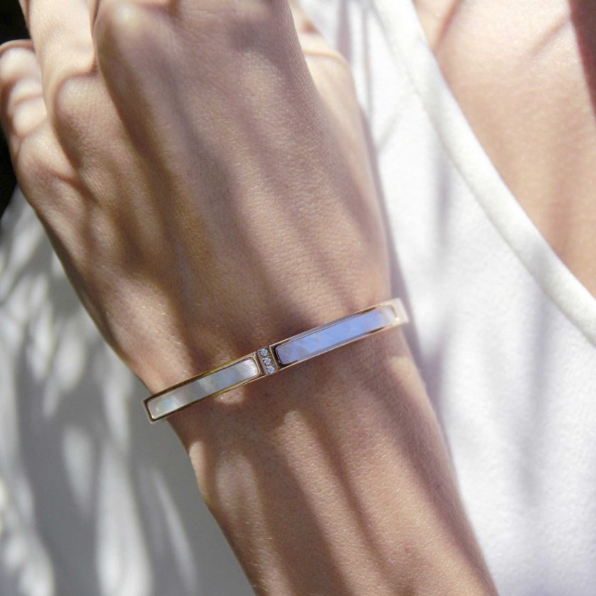 mano de mujer con pulsera rígida de forma ovalada con nacar en toda la cara superior y terminación de cristales incrustados